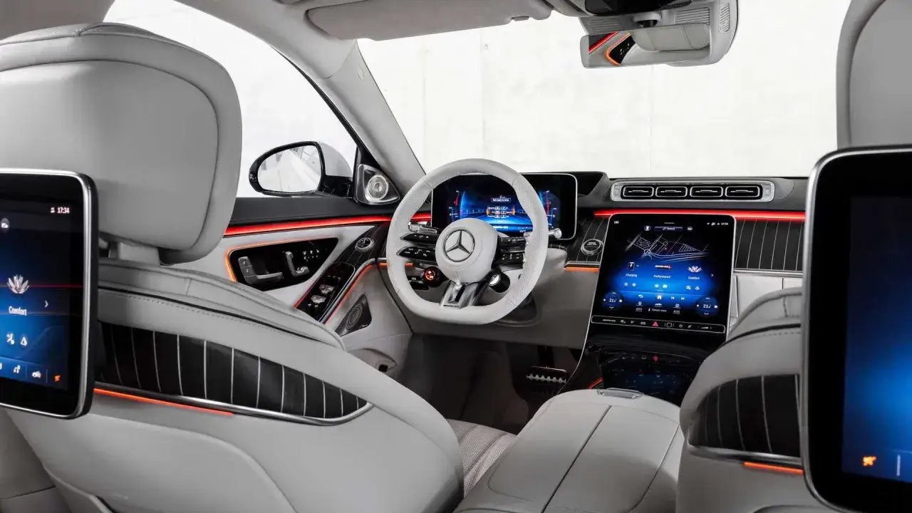 Wnętrze S 63 AMG Mercedes-Benz: luksusowe fotele, biała kierownica, wielkie ekrany i nastrojowe oświetlenie.