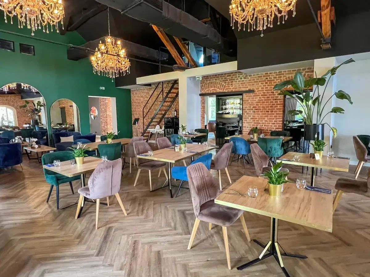 Eleganckie wnętrze restauracji, idealne miejsce, gdzie zjeść w Toruniu. Wygodne fotele, stylowe stoły i kryształowe żyrandole tworzą wyjątkową atmosferę.