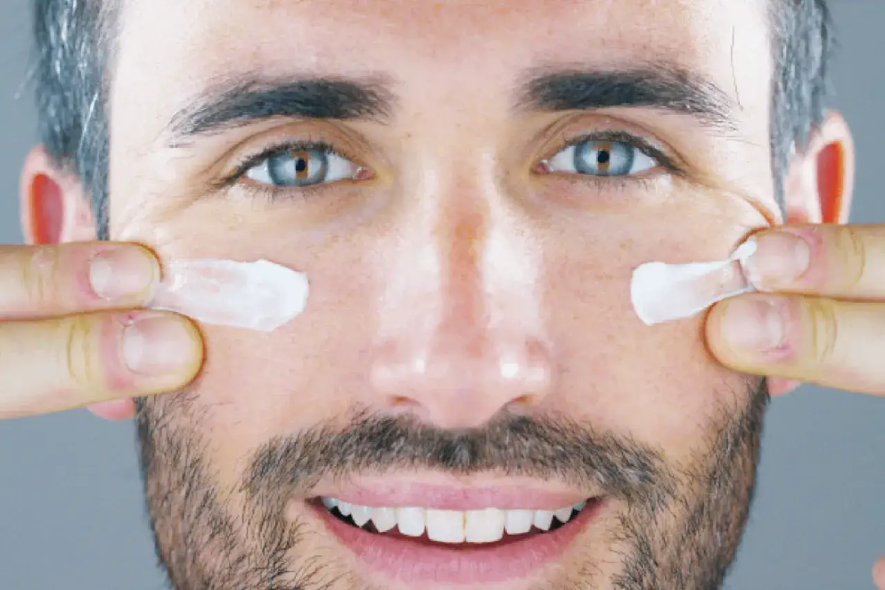 Hombre aplicando crema para combatir las arrugas en los ojos a los 40.