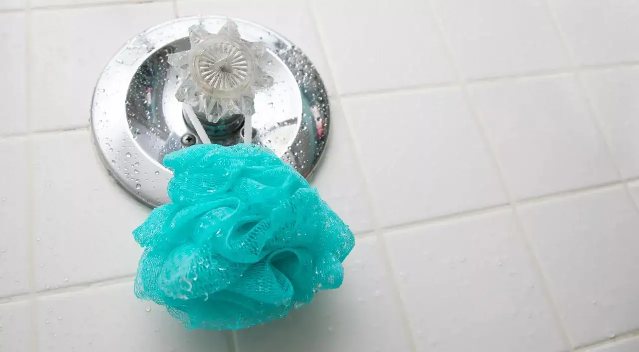 Ein t&uuml;rkiser Luffa Schwamm wird unter der Dusche gereinigt.