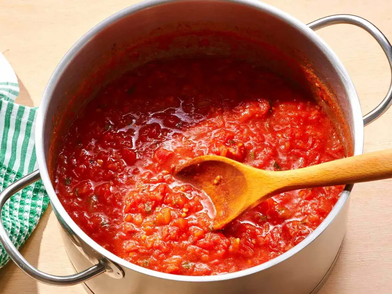 Ein Topf mit k&ouml;stlichem, hausgemachtem sugo di pomodoro, bereit zum Servieren. Eine Holzkelle r&uuml;hrt in der roten Sauce.