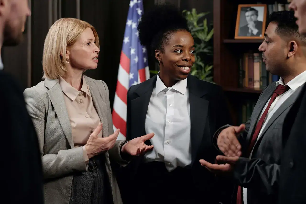 A diverse group discusses accelerated online MPA programs, with an American flag in the background.