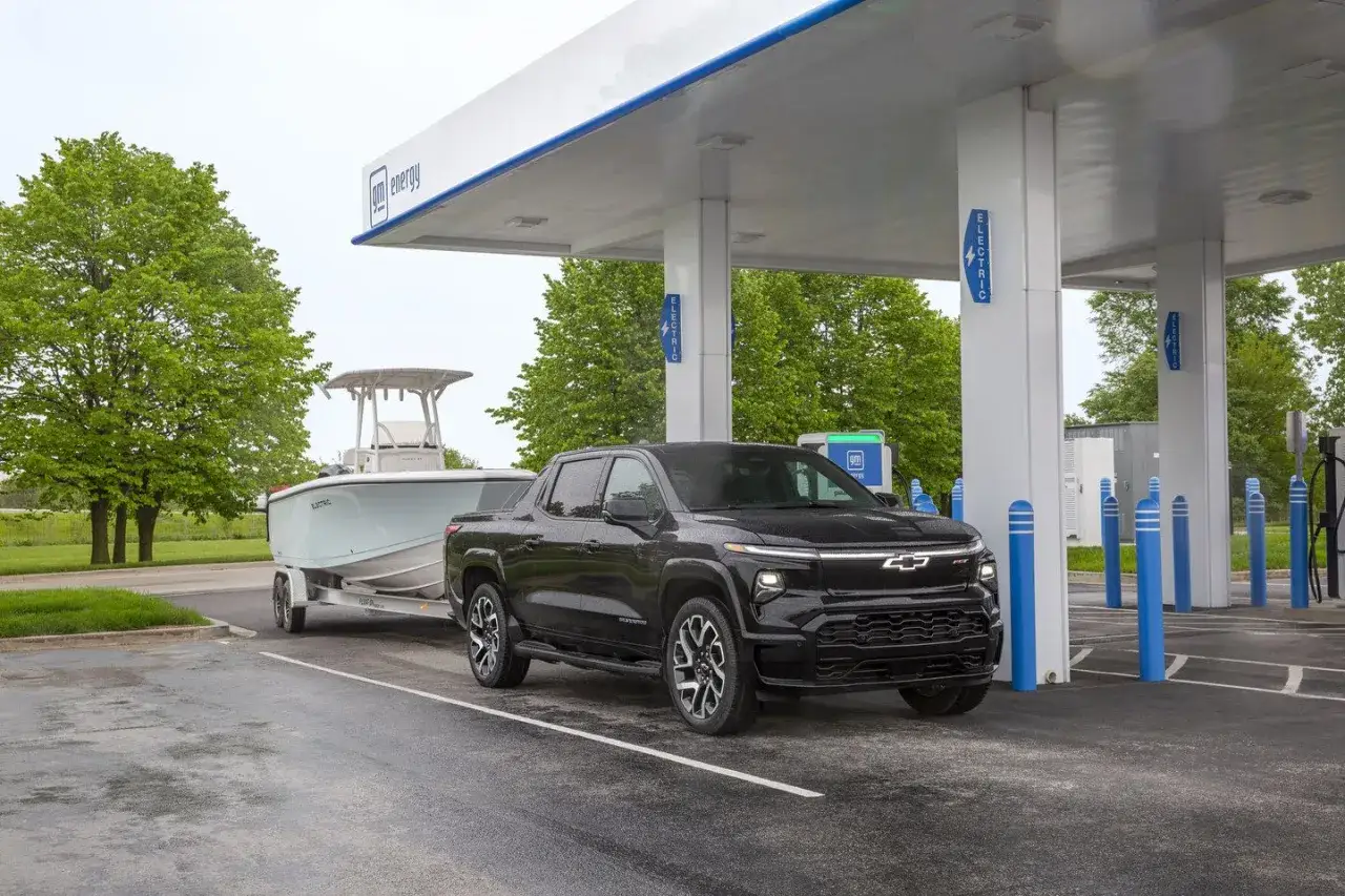 Czarny elektryczny pickup holuje ł&oacute;dź do stacji ładowania GM Energy.