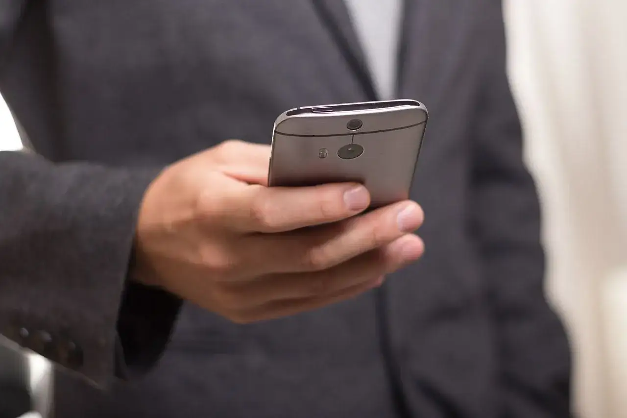 Mężczyzna w garniturze trzyma smartfon, planując sw&oacute;j roaming międzynarodowy.