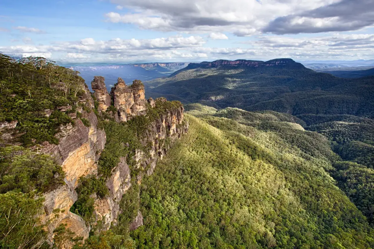 Drei Schwestern Felsen, ein Wahrzeichen Australiens, ragen aus einer &uuml;ppigen, gr&uuml;nen Landschaft unter einem dramatischen Himmel hervor. Ein Muss f&uuml;r jeden Australien-Fan.