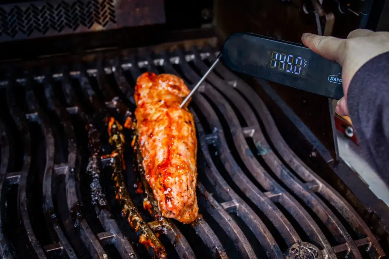 Grilla vildsvin ryggbiff på grillen, en termometer visar temperaturen.