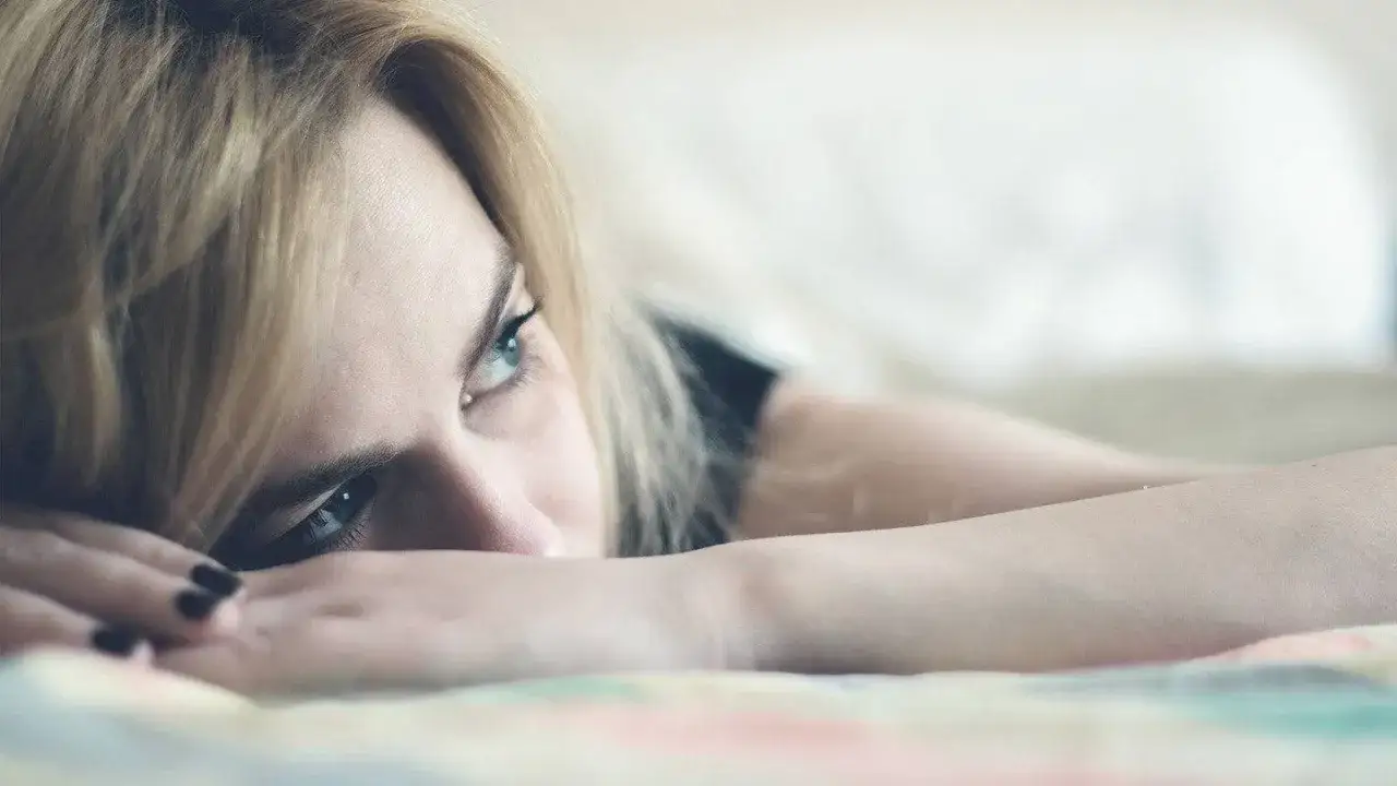 Occhi azzurri e capelli biondi, un volto pensieroso su un letto. Un momento di riflessione, un pensiero che dice: 