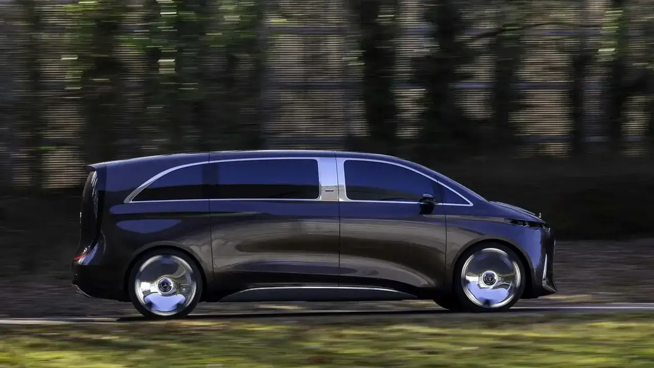 Futurystyczny minivan Kia PV5 w ciemnym kolorze, poruszający się po drodze wśród rozmytych drzew.