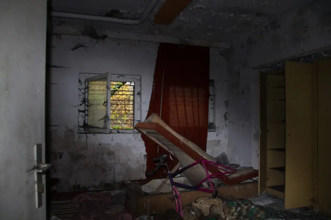 Interno di una casa stregata, con un letto rovesciato, una bicicletta rosa e un armadio aperto.