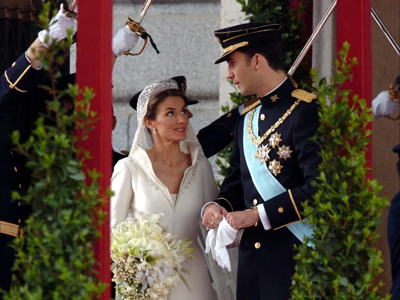 Novios en su boda, un d&iacute;a que celebra bodas de plata, oro y platino. Ella, radiante con velo y ramo; &eacute;l, con uniforme militar.