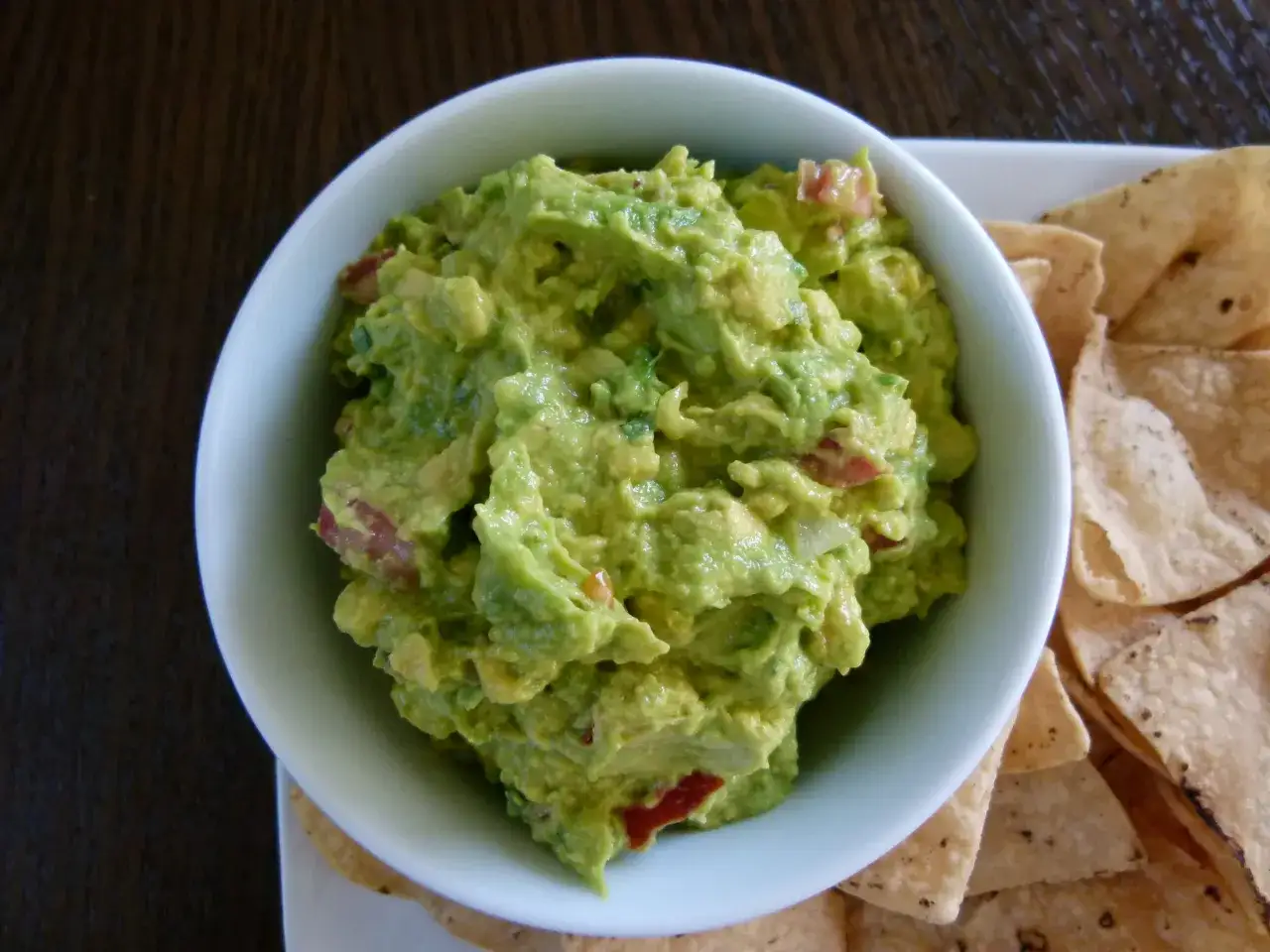 Frisches Guacamole-Rezept in einer Schüssel, serviert mit Tortilla-Chips. Cremig, grün und voller Geschmack.