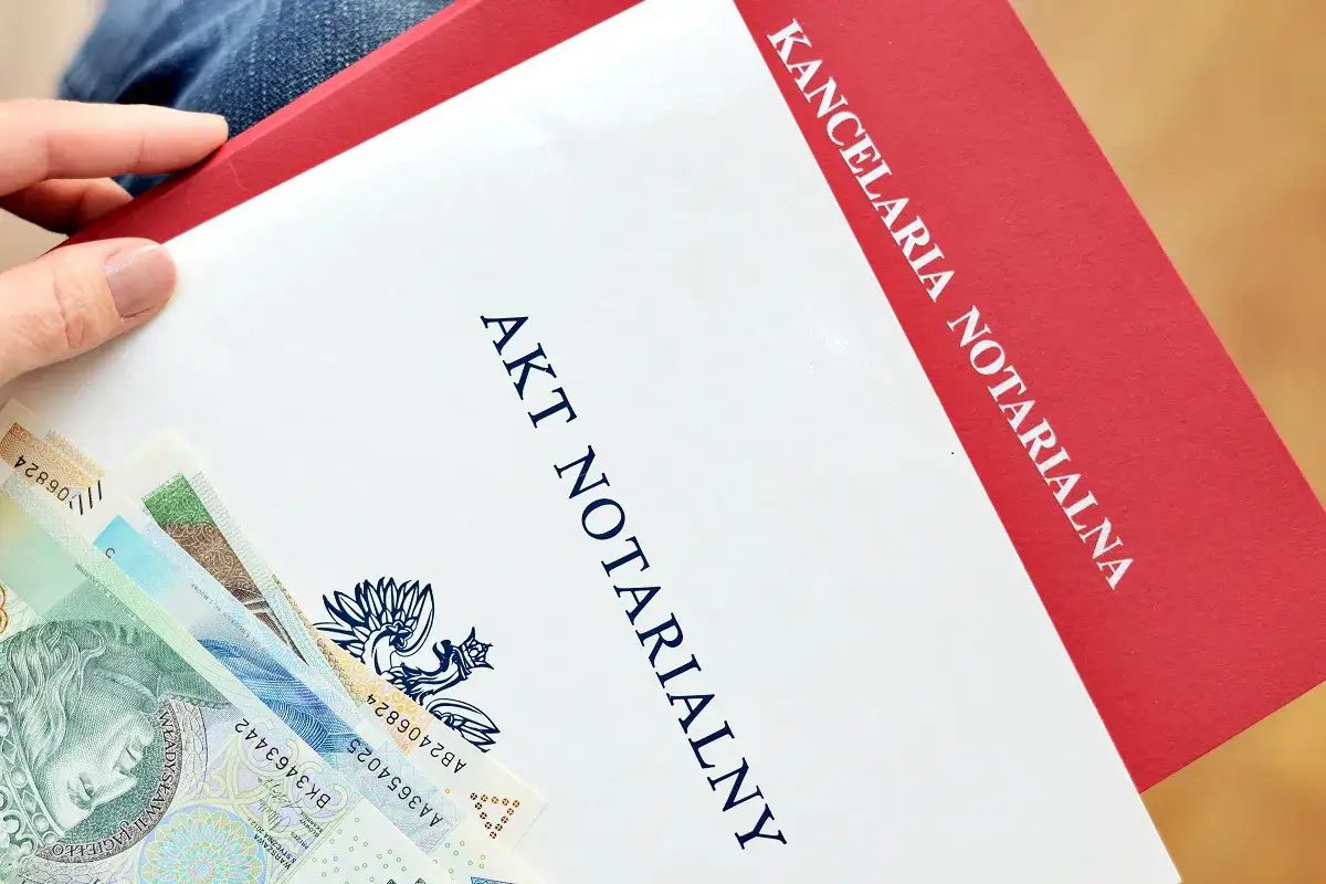 Akt notarialny z widocznymi banknotami. Kancelaria notarialna przygotowuje dokumenty, a taksa notarialna jest częścią kosztów.