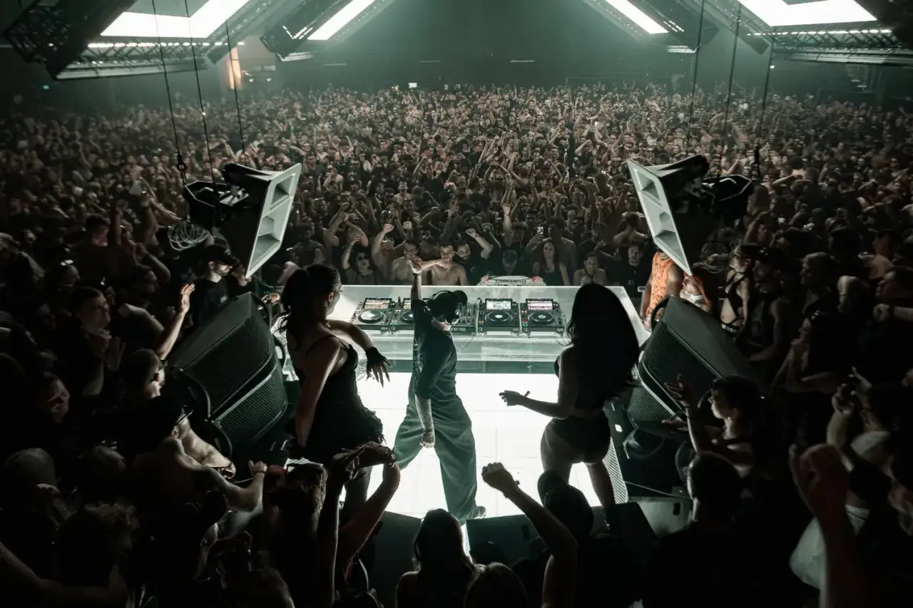 Multitud en &eacute;xtasis ante el DJ, un **outworld klangkuenstler** creando un ambiente hipn&oacute;tico en la pista de baile.