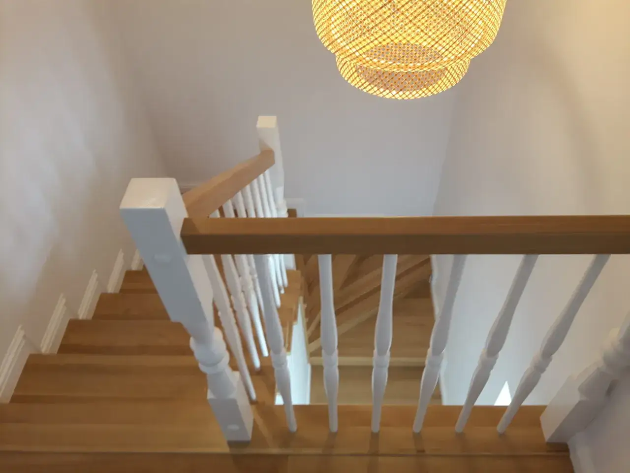Drewniane stopnie i białe balustrady tworzą klasyczną klatkę schodową w stylu angielskim.