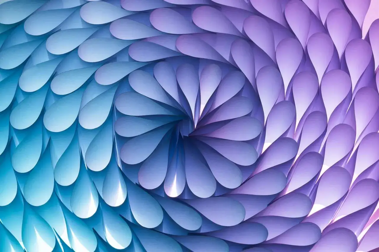 A mesmerizing pattern in art, formed by layered paper petals in a spiral of blues and purples, creating a sense of depth and movement.