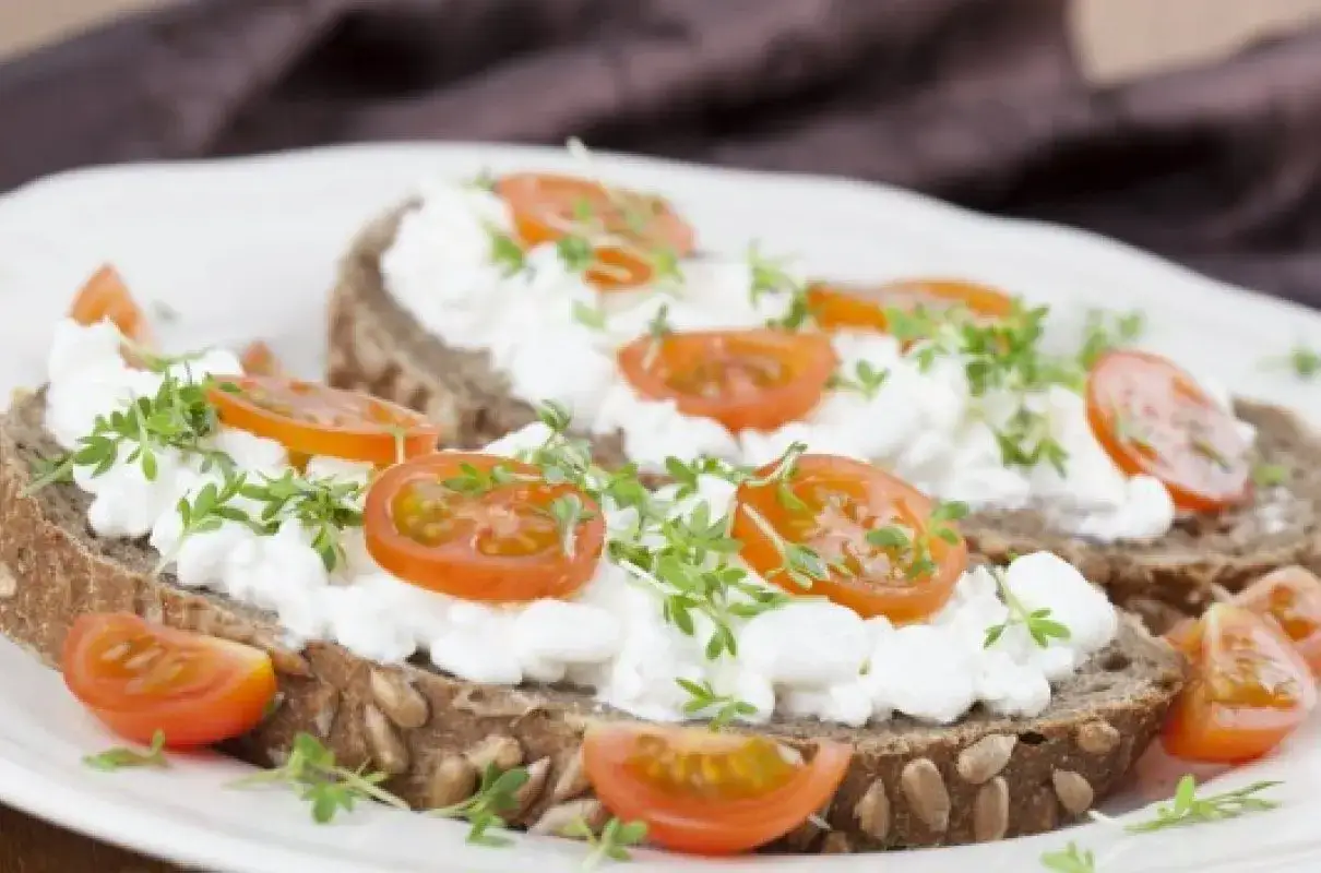 Dwa tosty z ciemnego pieczywa z twarożkiem, pomidorkami koktajlowymi i kiełkami. Idealny obiad 1000 kcal.