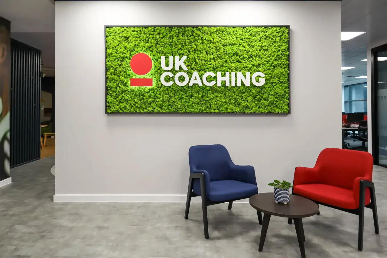 A modern office space with a vibrant green moss wall featuring the 