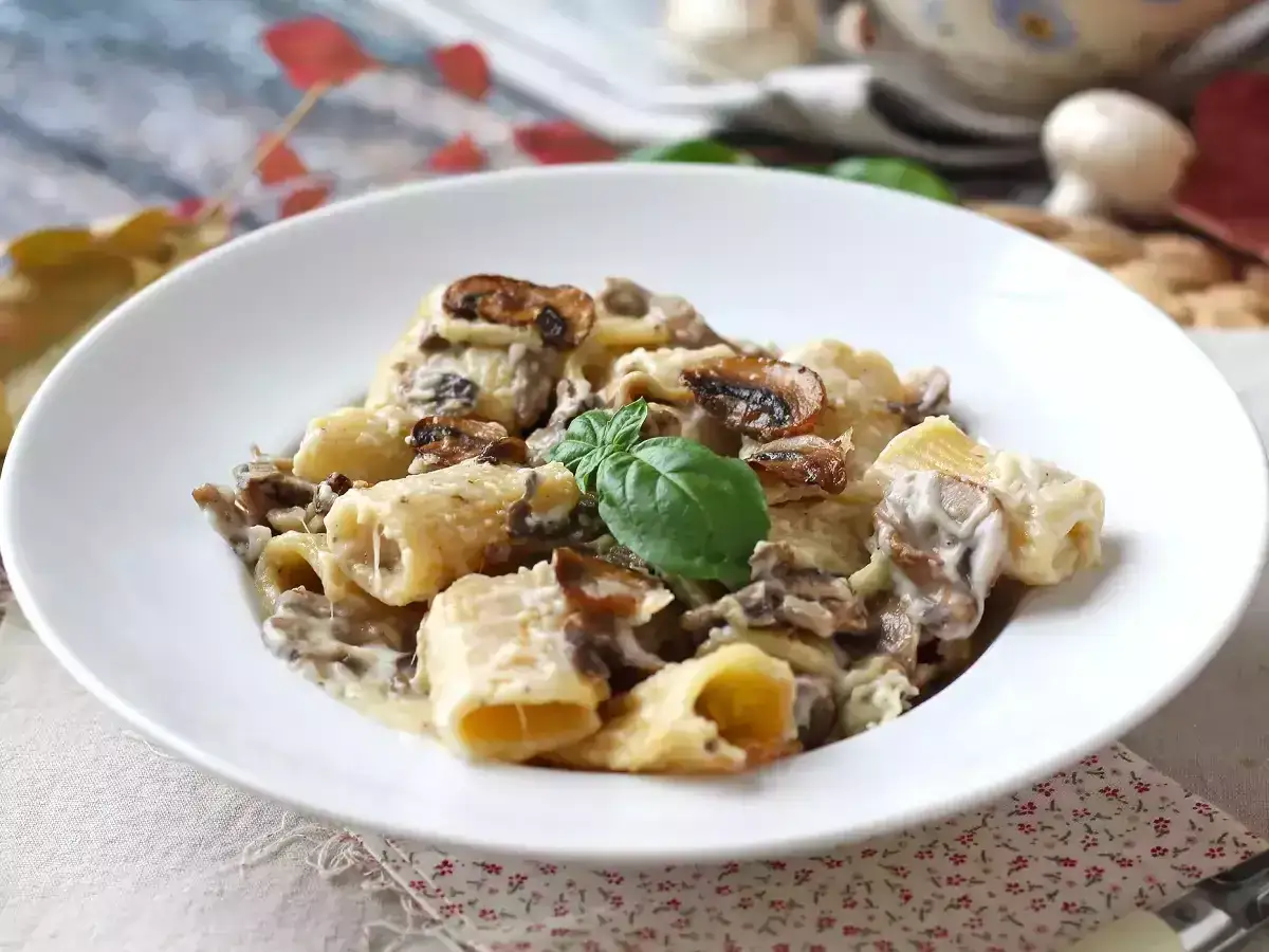 Deliciosa pasta con champi&ntilde;ones cremosos y un toque de albahaca fresca, servida en un plato blanco.
