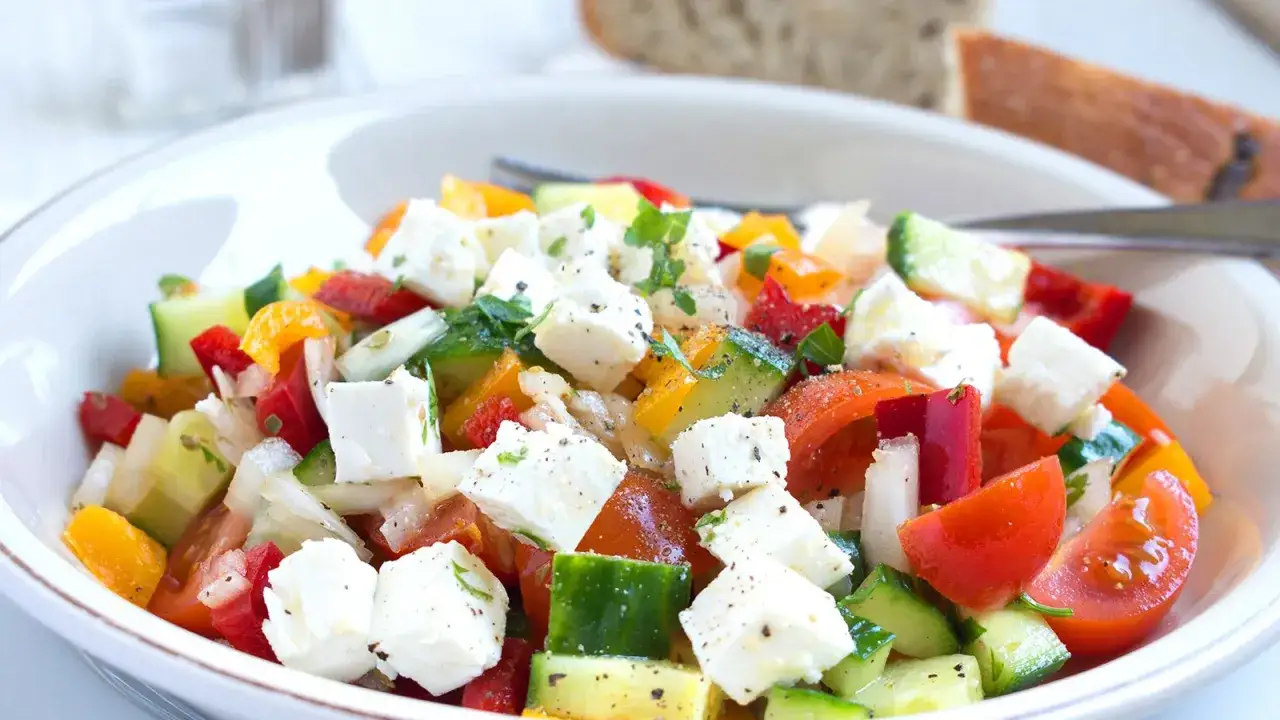 Frischer Paprika Gurken-Salat mit Feta, Tomaten und Zwiebeln, garniert mit Kräutern. Ein leichter Genuss!