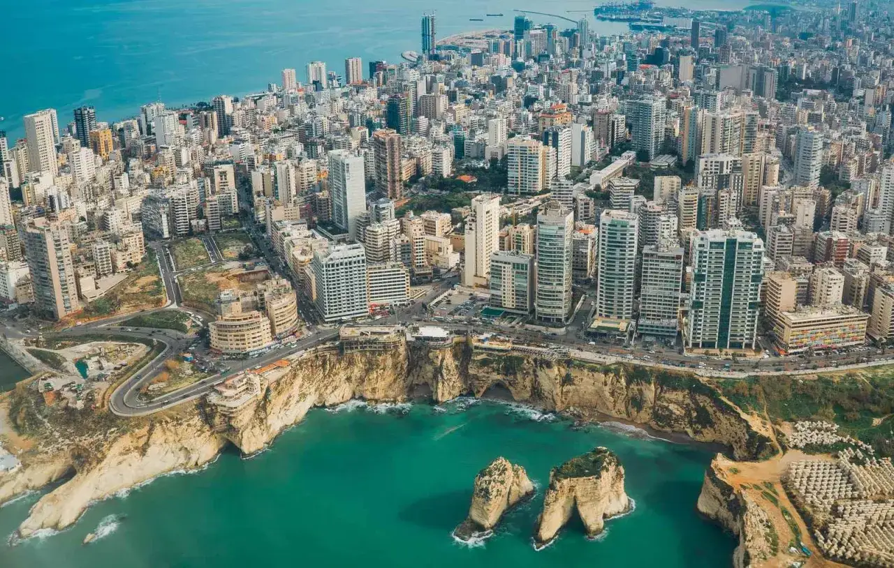 Aerial view of Beirut's coastline, showcasing the Pigeon Rocks and a dense cityscape. This vista is perfect for planning your Lebanon itinerary.