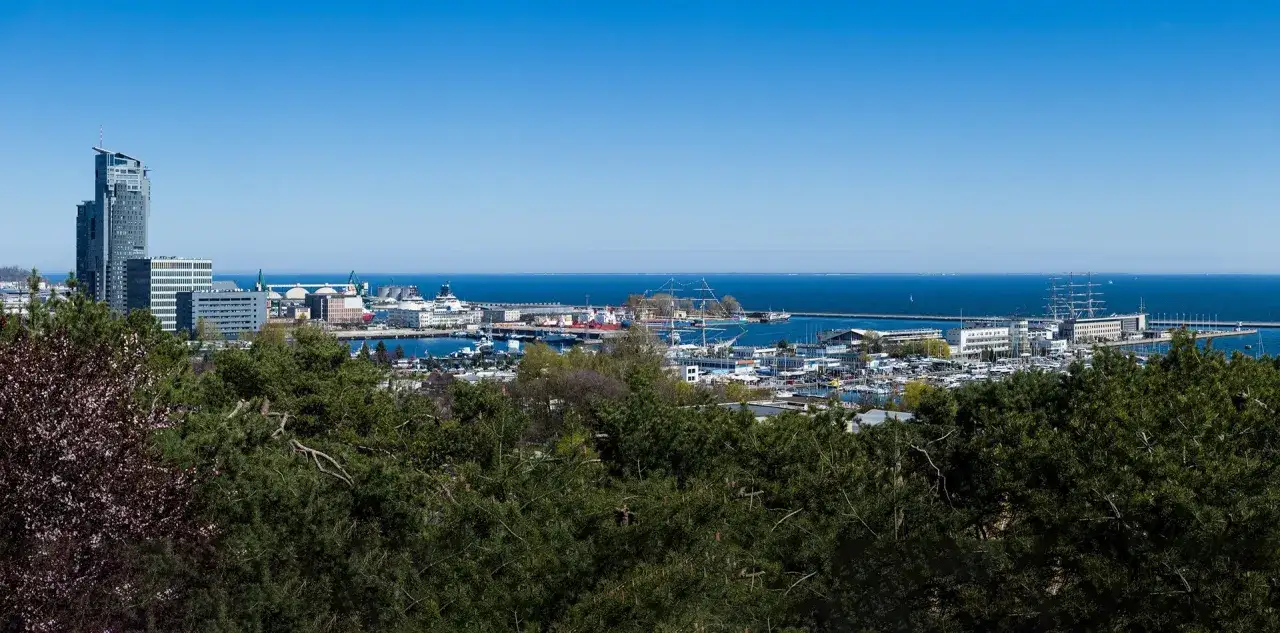 Widok na port w Gdyni z żaglowcami i nowoczesnymi budynkami. Marzenie o podr&oacute;ży kolejką linową nad tym krajobrazem.
