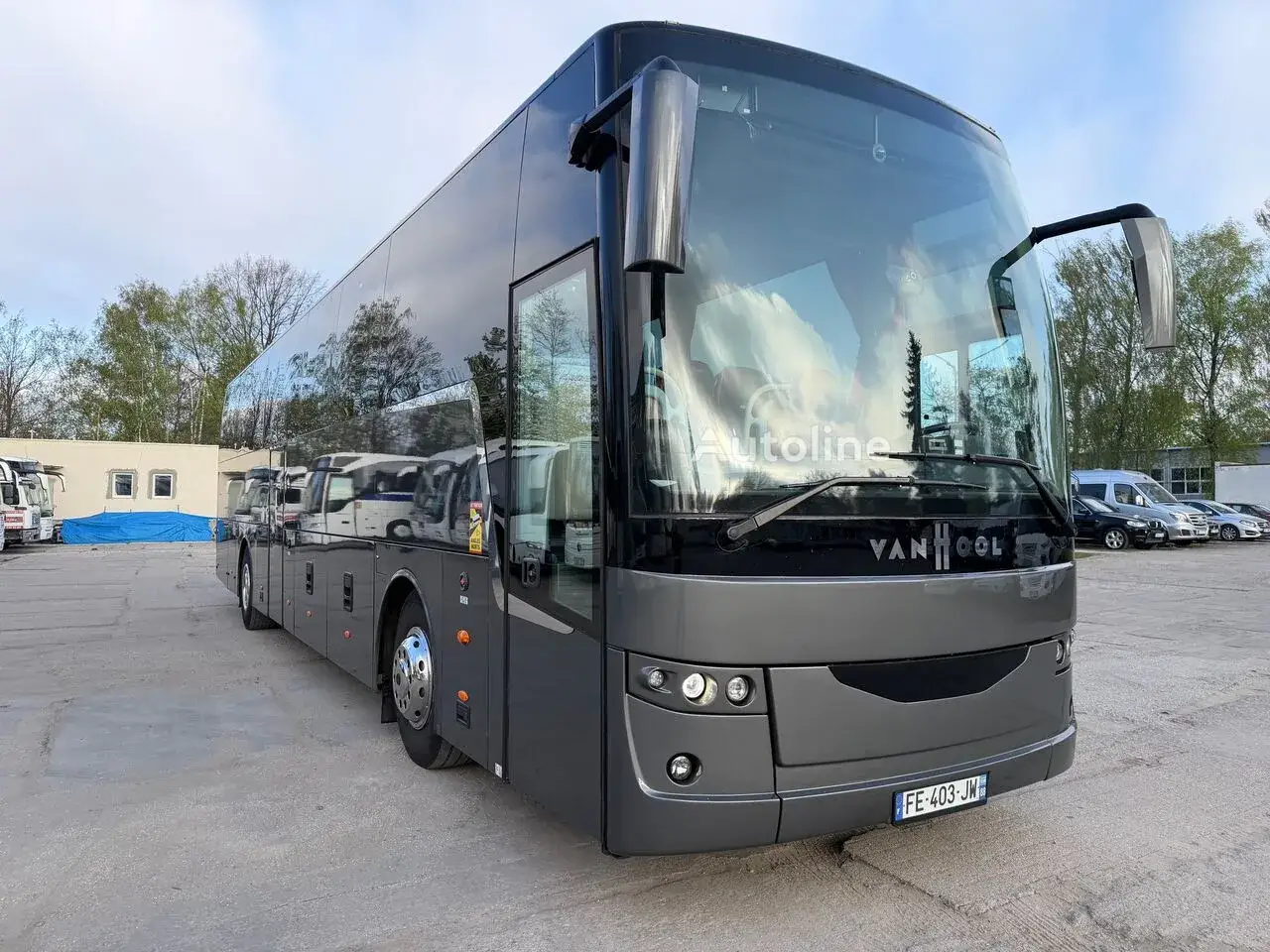 Nowy, szary autokar Van Hool z przyciemnianymi szybami stoi na placu.