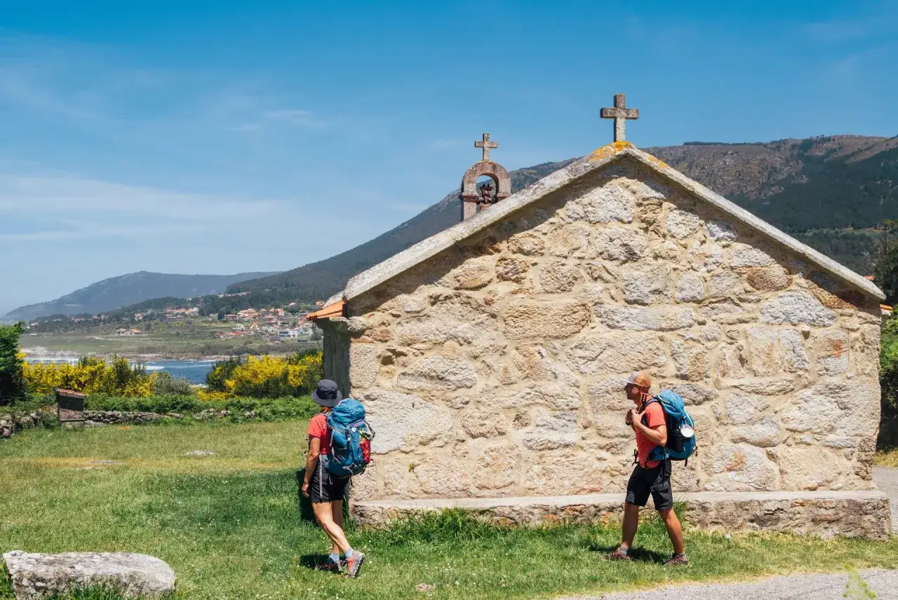 Pielgrzymi na szlaku z Polski do Santiago de Compostela mijają kamienną kapliczkę.