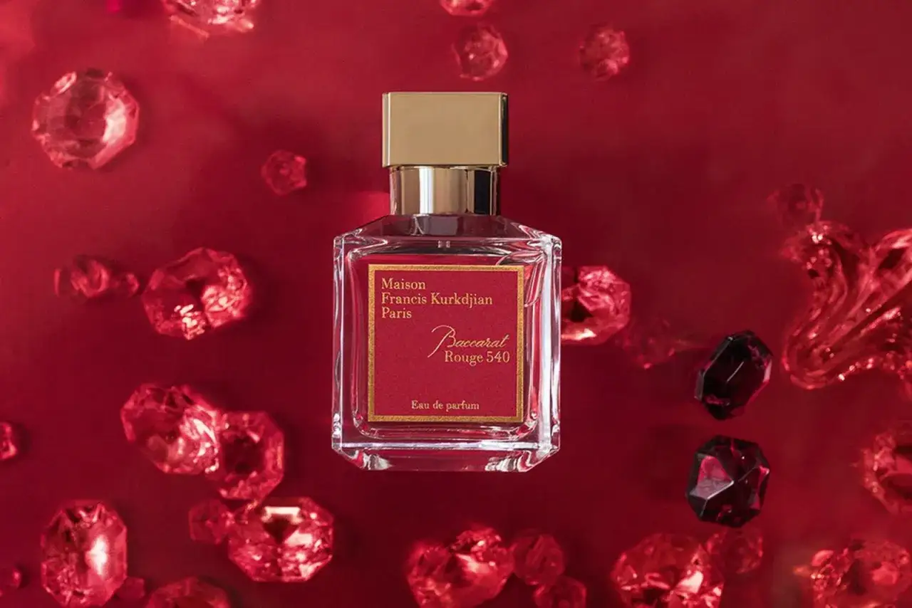 Elegancka butelka Maison Francis Kurkdjian Baccarat Rouge 540 otoczona lśniącymi, czerwonymi kryształami.