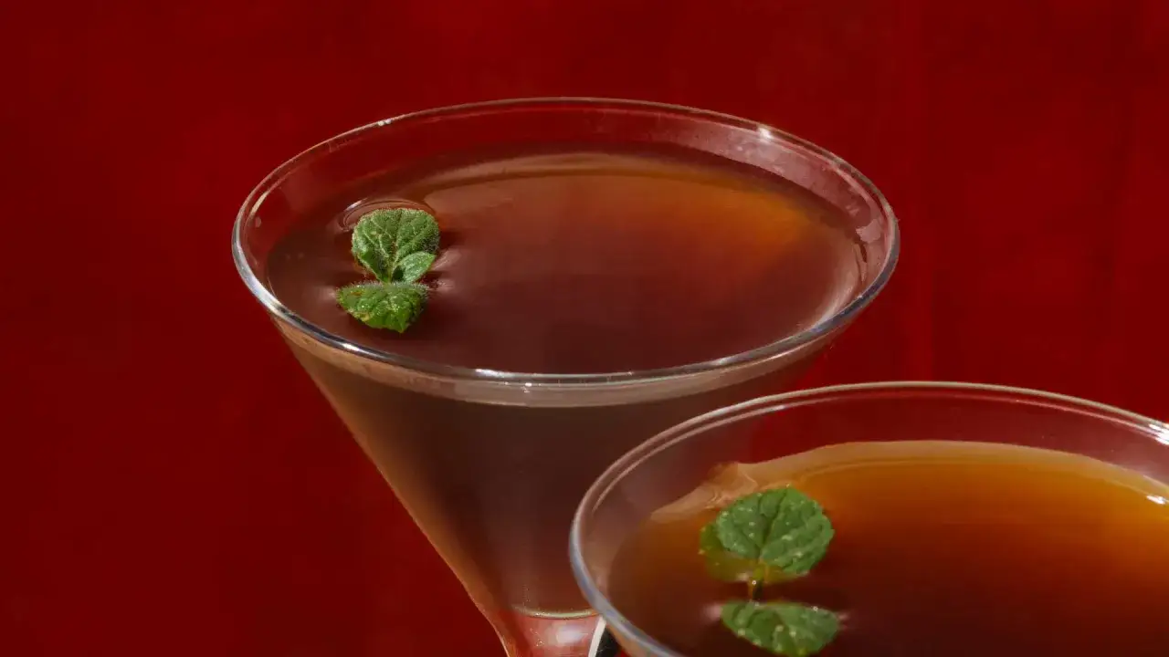 Due cocktail Stinger IBA, con liquore al caff&egrave; e menta, serviti in coppette da martini su sfondo rosso.