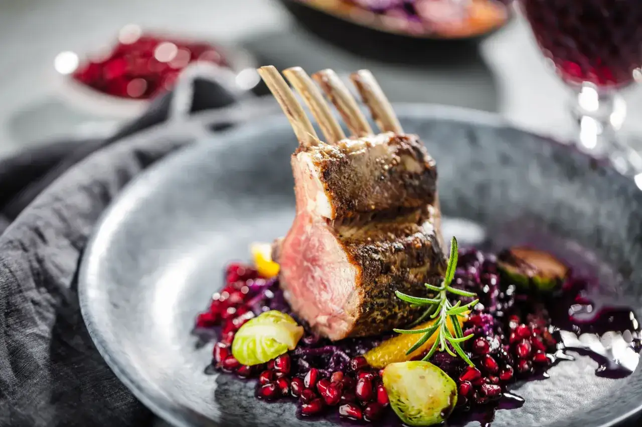 Carr&eacute; d'agneau 1 kg, parfaitement r&ocirc;ti, servi avec une garniture color&eacute;e de grenade, chou rouge et romarin. Le temps de cuisson id&eacute;al pour ce plat est essentiel.