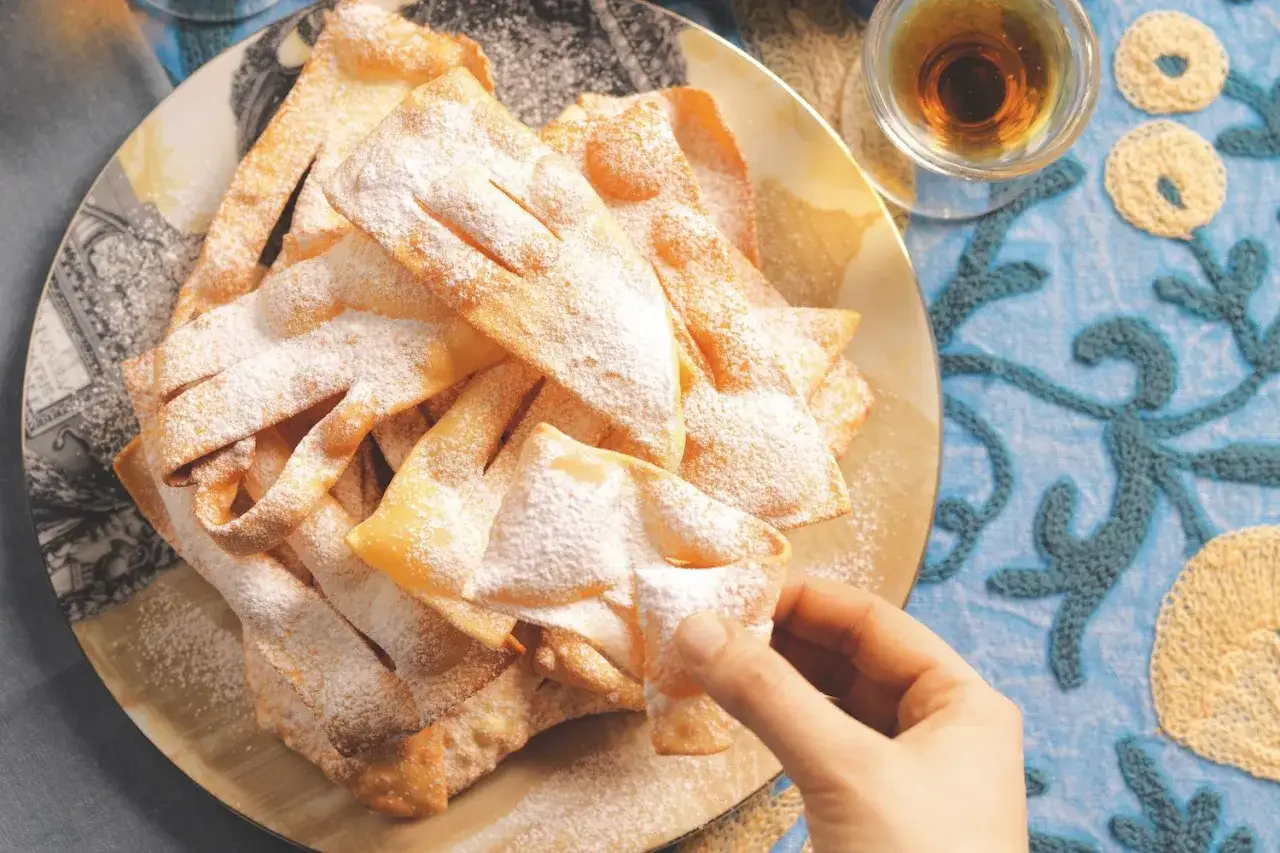 Un piatto di frappe croccanti, spolverate di zucchero a velo, pronte per essere gustate. Una deliziosa frappe ricetta per ogni occasione.