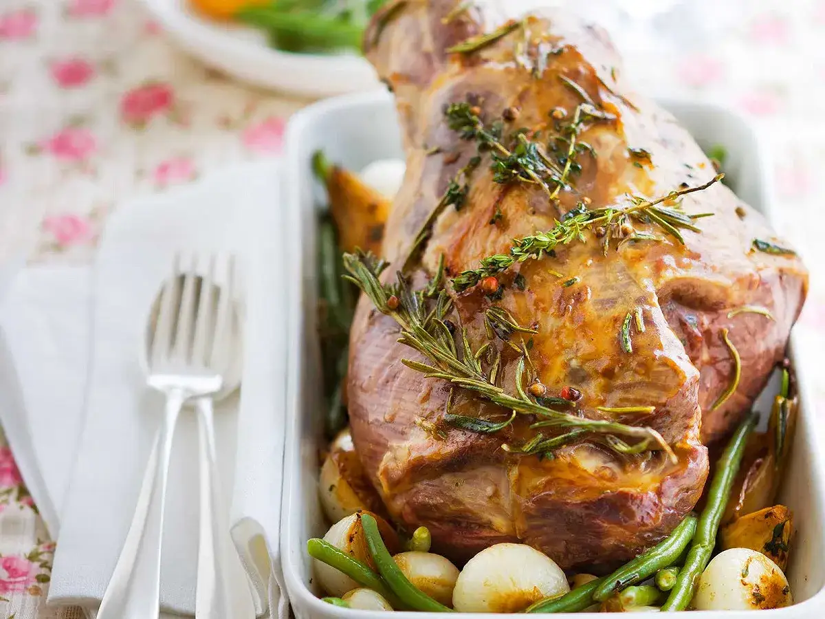 Gigot d'agneau désossé au four, doré et savoureux, garni de romarin et servi avec des légumes rôtis.