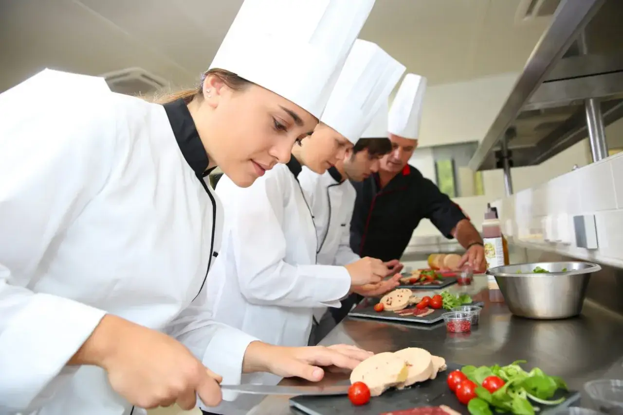 Giovani chef imparano da su chef chi &egrave; un maestro in cucina, preparando piatti raffinati con ingredienti freschi.