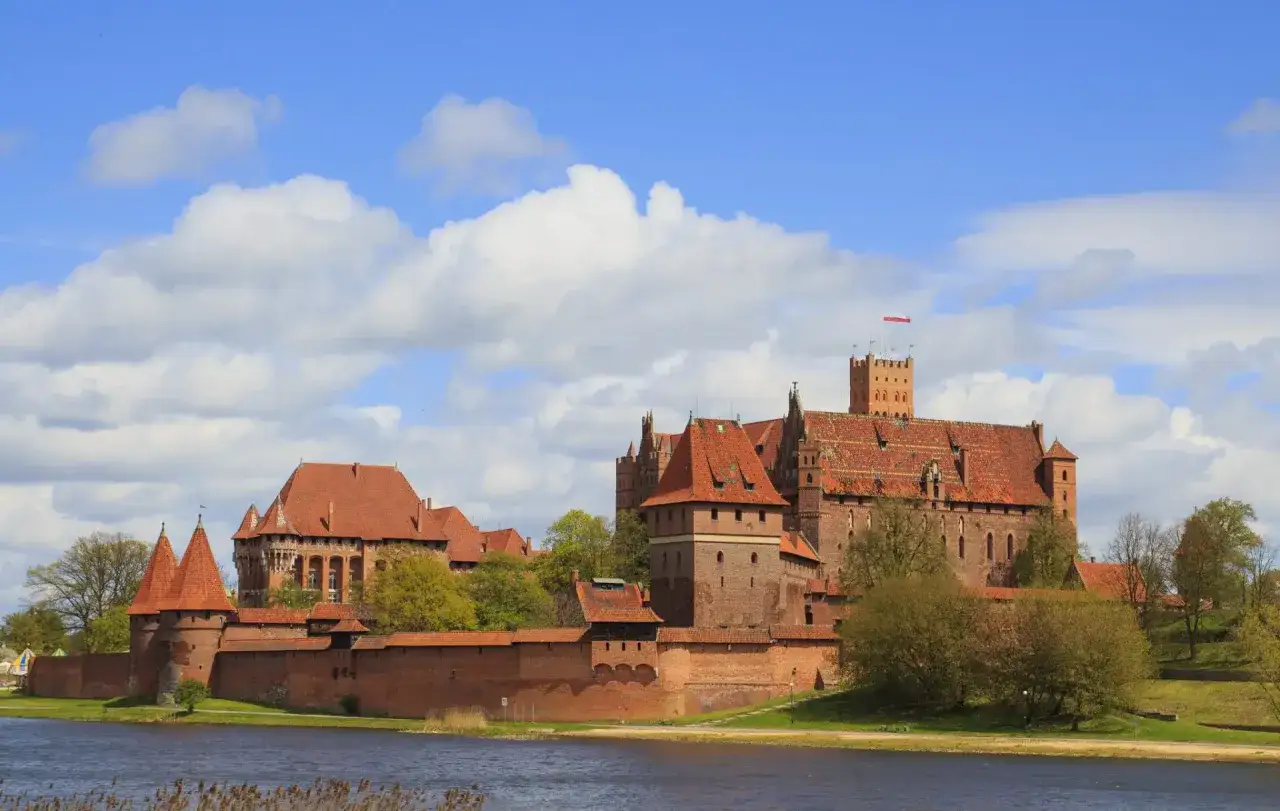 Potężny zamek w Malborku, którego budowa rozpoczęła się w XIII wieku, góruje nad rzeką.