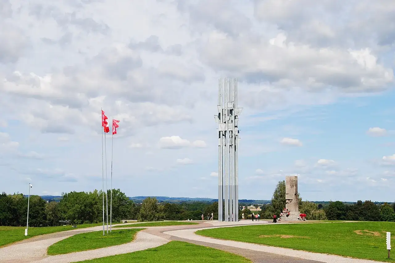 Grunwald atrakcje: nowoczesny pomnik i historyczna wieża na tle błękitnego nieba z chmurami.