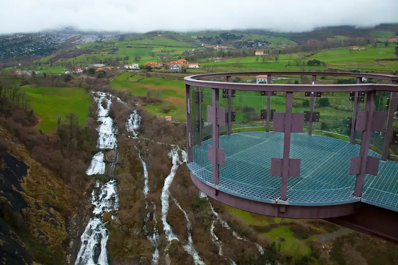 Mirador Siguenza con cascadas y un pueblo en la ladera verde.