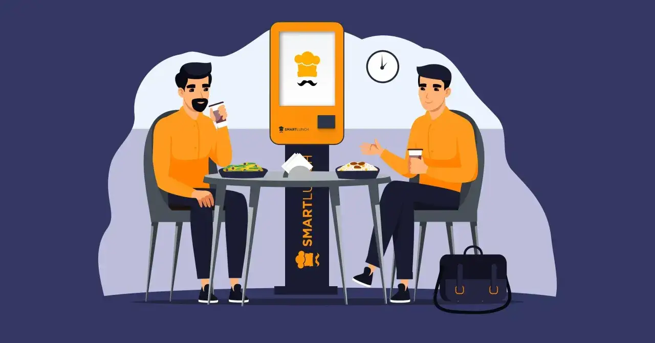 Dwóch mężczyzn przy stoliku, każdy z napojem i miską jedzenia, korzysta z przerwy na posiłek regeneracyjny. Obok stoi automat z logo SmartLunch.