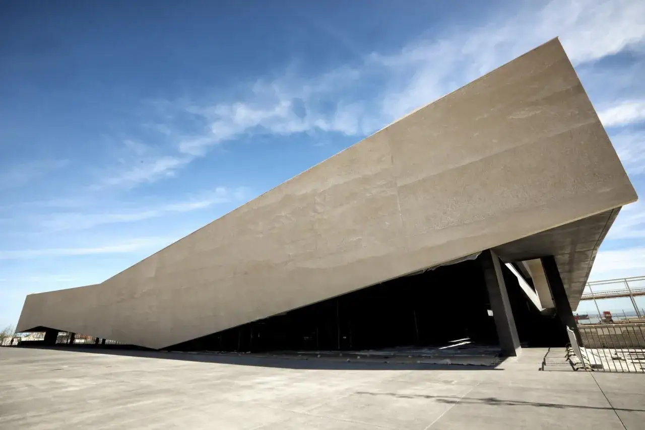 Edificio moderno con tetto spiovente al porto di Lisbona, sotto un cielo azzurro con nuvole bianche.