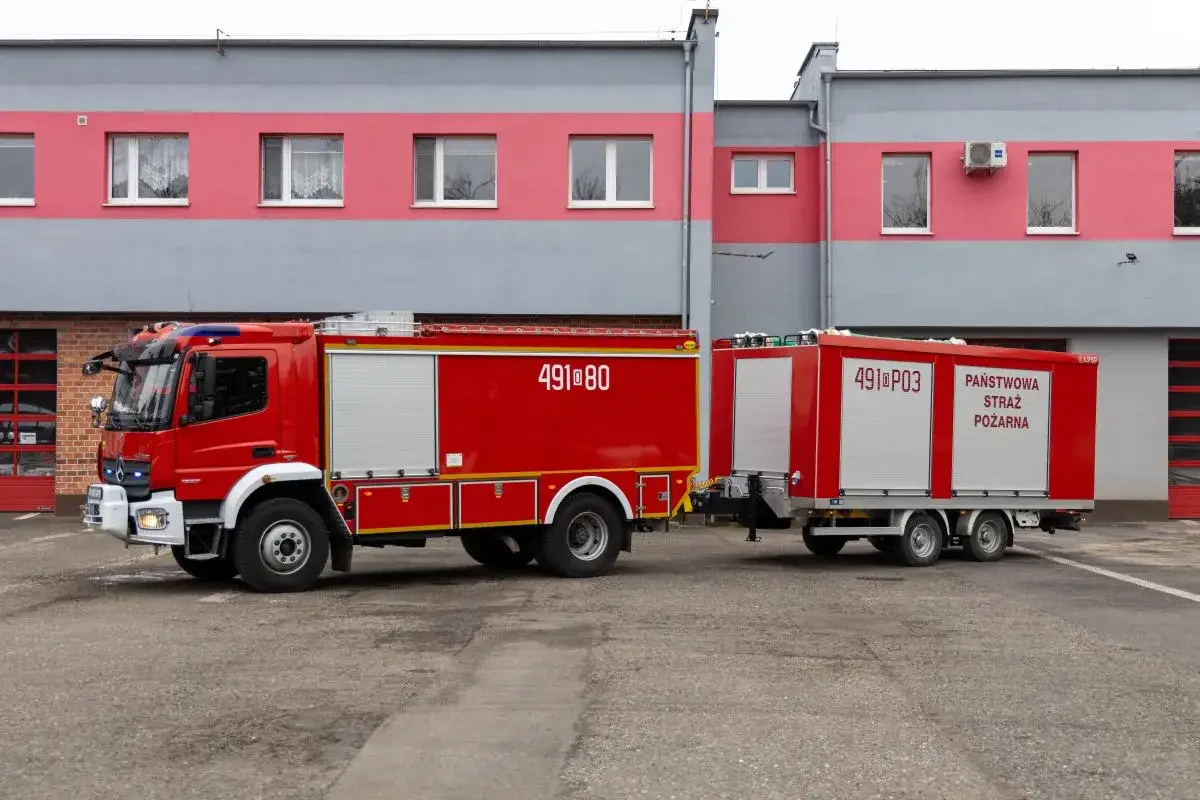 Czerwony wóz strażacki z przyczepą, gotowy do akcji. Ta potężna maszyna, wyposażona w wydajną pompę ssawną, to symbol bezpieczeństwa.
