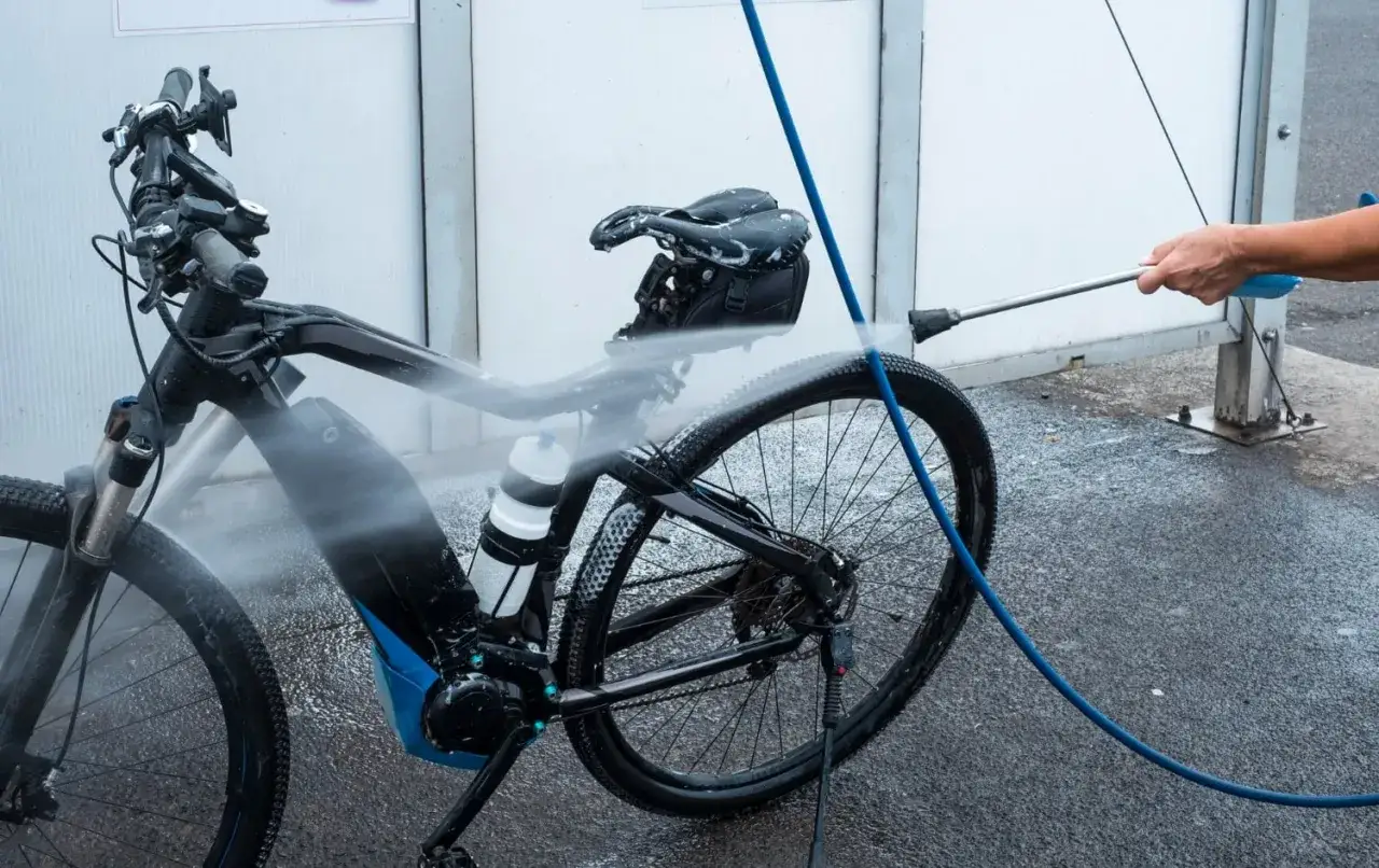 Czyszczenie elektrycznego roweru na myjni. Woda spływa po ramie i kołach, przywracając mu blask po błotnistych trasach.