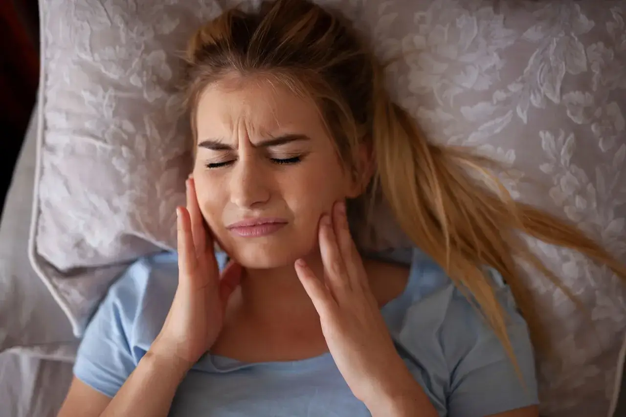 Mujer con dolor de mandíbula, buscando cómo evitar el bruxismo.