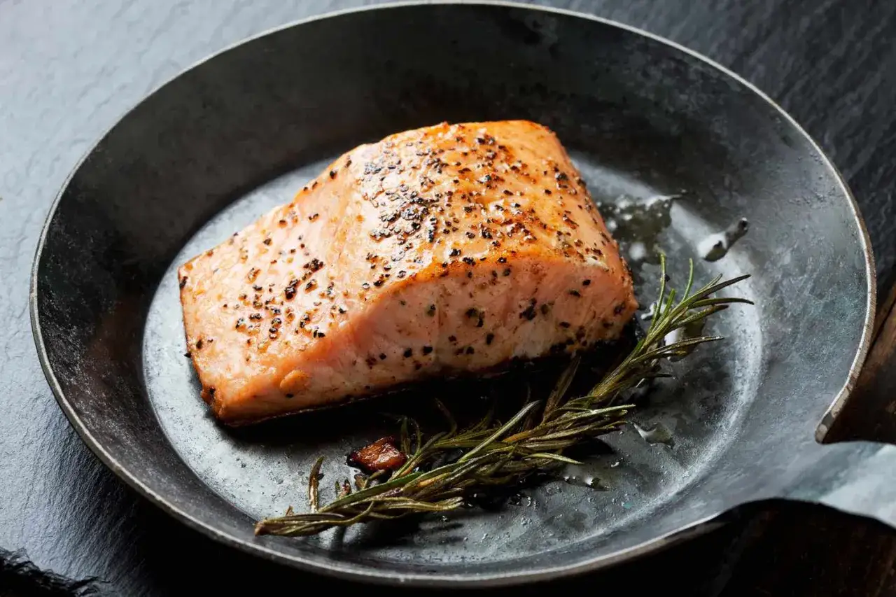 Perfekt gebratenes Wildlachsfilet mit Rosmarin in einer Pfanne. So einfach lässt sich ein köstliches Wildlachsfilet zubereiten.