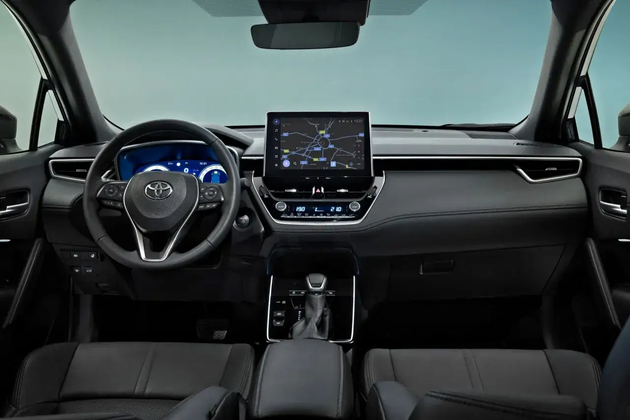 Wnętrze nowej Toyoty Corolli Cross: kierownica, ekran multimedialny z nawigacją, dźwignia zmiany biegów i skórzane fotele.