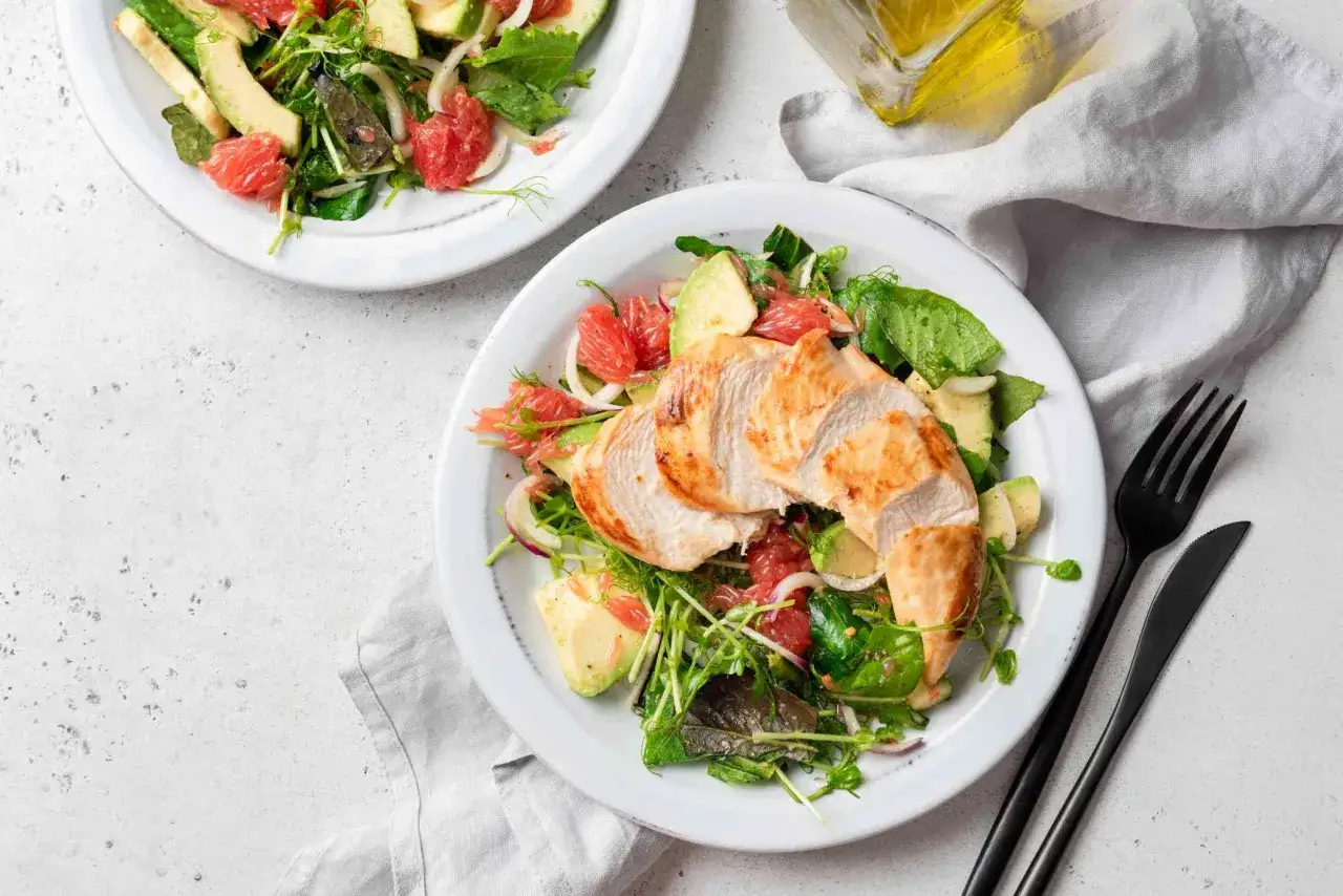 Insalata con petto di pollo grigliato, avocado, pompelmo e verdure miste. Un piatto gustoso e leggero, ideale per chi cerca cibi con tante proteine e pochi carboidrati.
