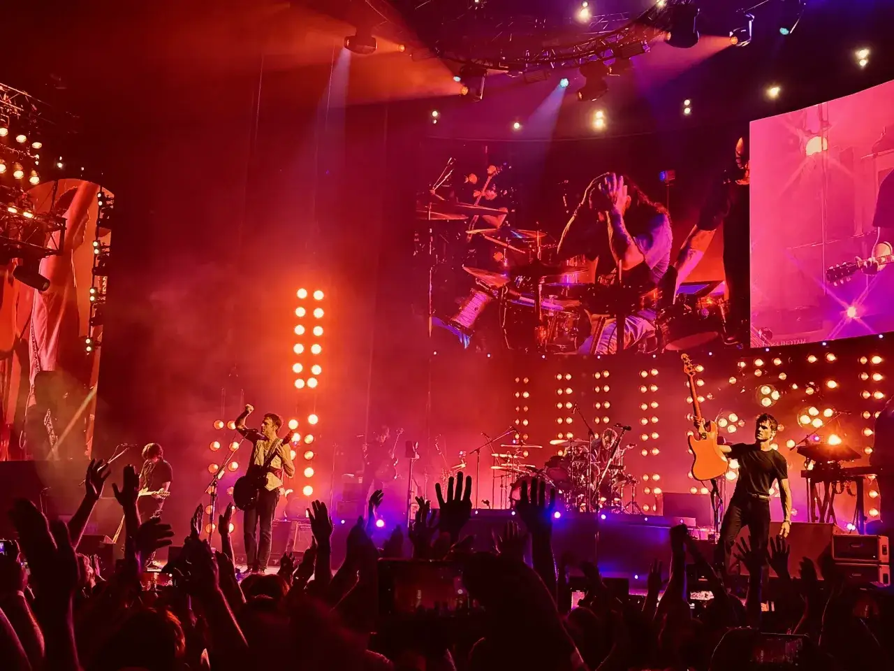 Koncert Kings of Leon w Polsce. Fani w ekstazie, muzycy na scenie, czerwone i fioletowe światła.