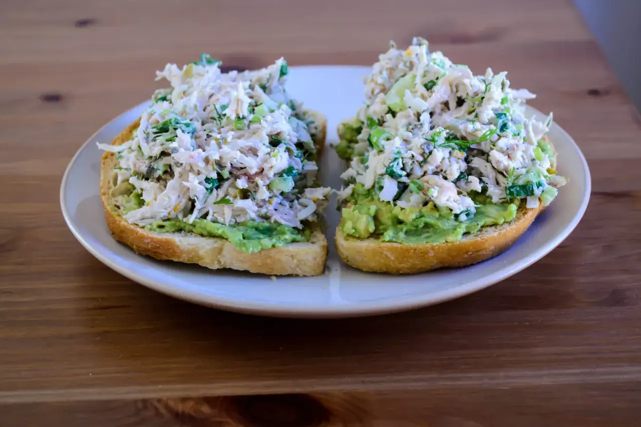 Två skivor rostat bröd med avokado och en generös topping av kycklingsallad. Ett enkelt och gott kycklingsallad recept för en snabb lunch.