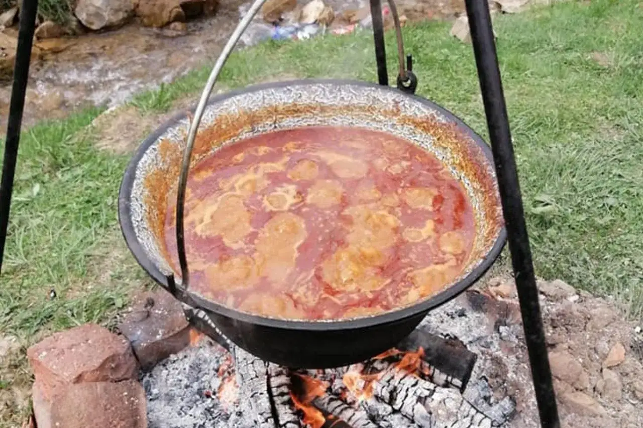 Gulasz z kociołka bulgocze nad ogniskiem, pachnąc wspaniale. Aromatyczny, sycący posiłek gotuje się powoli, nabierając głębi smaku.