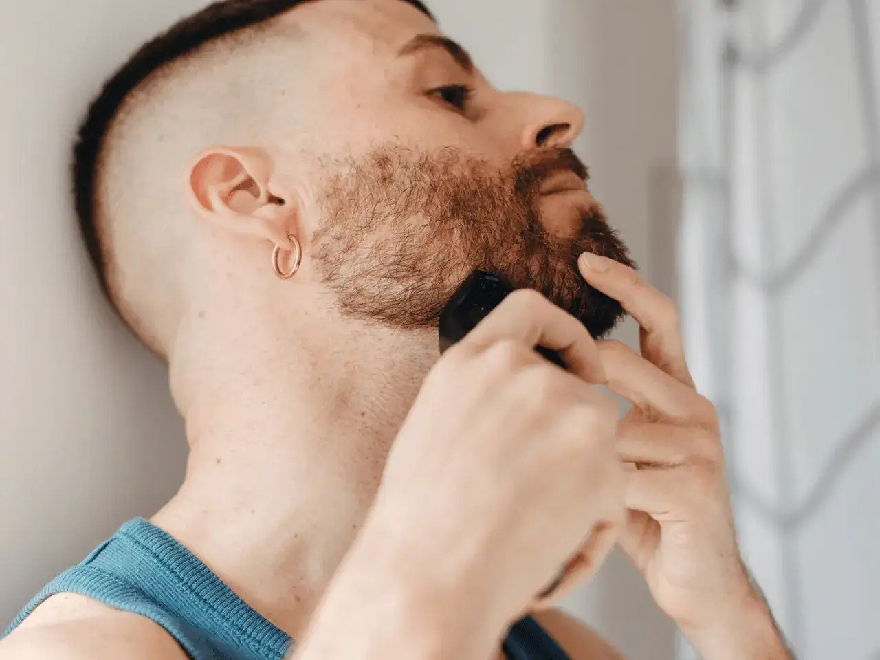 Hombre con barba recortando su cuello, decidiendo hasta donde afeitarse el cuello.