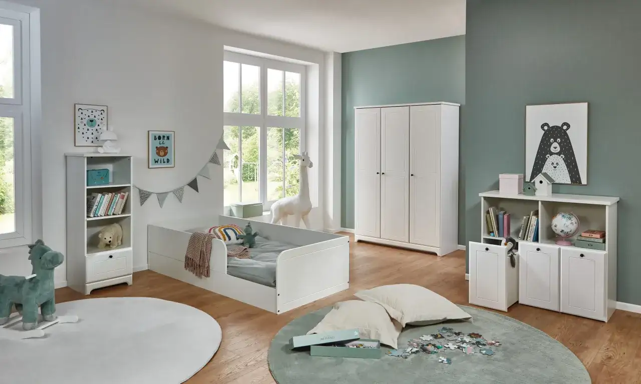 Ein heller, aufgeräumter **Minimalismus Kinderzimmer** mit weißem Bett, Kleiderschrank und Regal. Spielzeug und Deko sind liebevoll platziert.