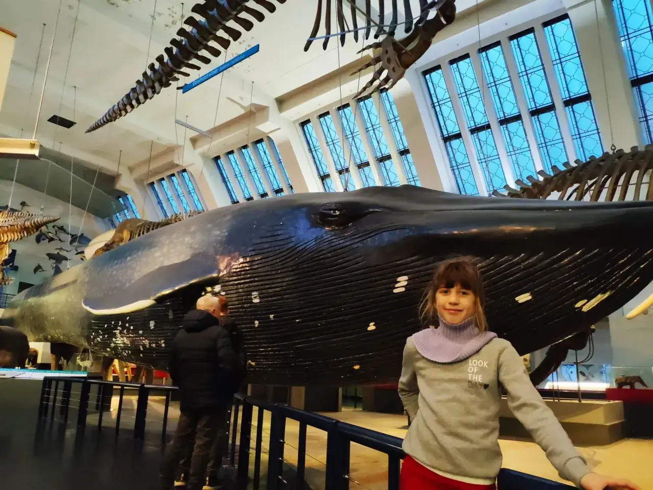 Dziewczynka pozuje przy gigantycznym szkielecie wieloryba w muzeum sztuki naturalnej w Londynie.